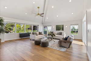 Living area with ceiling fan, healthy amount of natural light, high vaulted ceiling, wood-type flooring, and recessed lighting