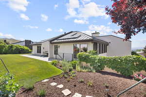 Rear view of house with a standing seam roof, a chimney, a patio area, a metal roof, and stucco siding