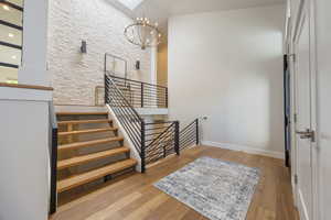 Stairway with a chandelier, recessed lighting, wood finished floors, and a high ceiling entry.