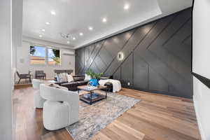 Living room with a decorative wall, recessed lighting, and wood finished floors