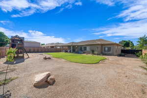 Rear view of house featuring a fenced backyard, a playground, stucco siding, and a tile roof