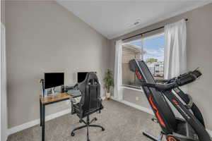 Carpeted office space with vaulted ceiling and baseboards