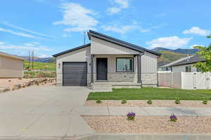 View of front facade with a mountain view, driveway, a garage, and stone siding