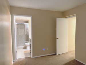 Unfurnished bedroom featuring carpet floors, connected bathroom, and baseboards