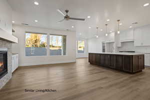 Kitchen with a stone fireplace, light countertops, a ceiling fan, recessed lighting, and black stovetop
