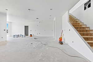 Unfurnished living room with stairs and concrete flooring