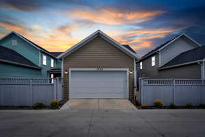 View of front of house featuring concrete driveway, a gate, and a garage
