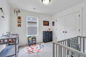 Bedroom with carpet floors, a closet, and a nursery area