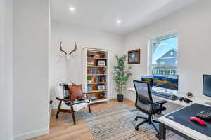 Office with light wood-style flooring and recessed lighting