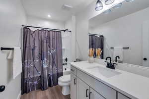 Full bathroom with wood finished floors, vanity, and shower / tub combo