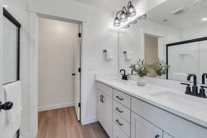 Full bath featuring double vanity, wood finished floors, and a shower stall