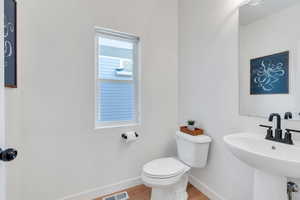 Half bath with baseboards and wood finished floors