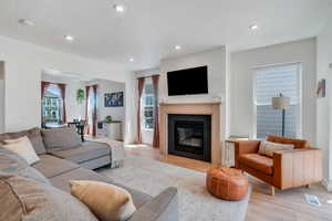 Living area featuring light wood-style floors, recessed lighting, and a glass covered fireplace