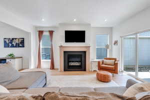 Living area featuring wood finished floors, a tile fireplace, plenty of natural light, and recessed lighting