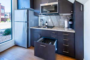 Kitchen featuring appliances with stainless steel finishes, light countertops, backsplash, light wood-style flooring, and modern cabinets