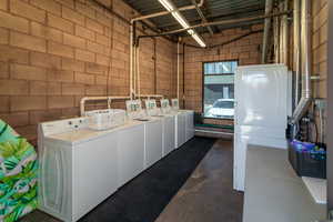 Laundry room featuring independent washer and dryer and concrete block wall