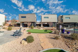 Back of property with a putting green, a patio area, and stucco siding