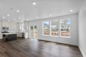 Kitchen featuring appliances with stainless steel finishes, dark wood-style floors, light countertops, a center island, and recessed lighting