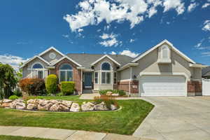 Ranch-style house with brick siding, stucco siding, a front lawn, and driveway