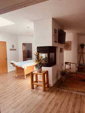 Living area featuring light wood-style flooring, a textured wall, a multi sided fireplace, and baseboards