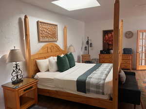 Bedroom featuring wood finished floors, a skylight, and a textured wall