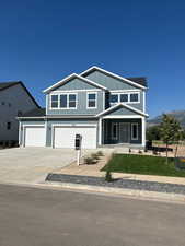 View of front facade with a mountain view, driveway, a front yard, an attached garage, and board and batten siding