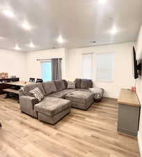 Living room with light wood-style floors, baseboards, a 9' ceiling, and recessed lighting