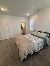 Carpeted bedroom featuring baseboards, recessed lighting, and ensuite bath