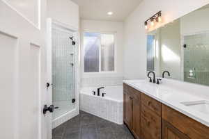 Bathroom with a shower stall, a bath, double vanity, and recessed lighting