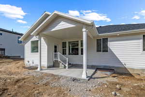 Rear view of property featuring a patio area and roof with shingles