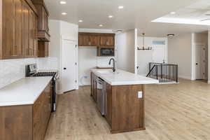 Kitchen featuring stainless steel appliances, decorative backsplash, light wood finished floors, recessed lighting, and light countertops