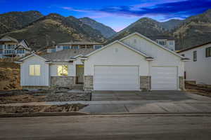 View of front of home featuring board and batten siding, an attached garage, driveway, a mountain view, and stone siding