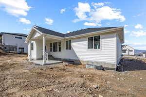 Rear view of house featuring a patio area and a shingled roof