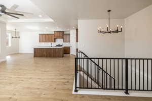 Kitchen with a chandelier, an island with sink, light countertops, recessed lighting, and light wood-style floors