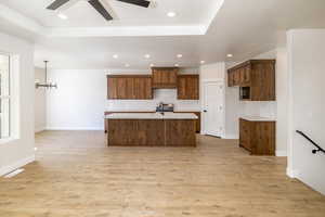 Kitchen with backsplash, light countertops, light wood-style floors, ceiling fan, and recessed lighting