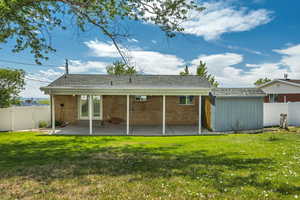 Back of house with a fenced backyard, a covered patio area, brick siding, a shingled roof, and a shed