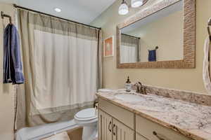 Bathroom featuring granite countertops, granite surround, linen closet, and shower / bath combo with shower curtain