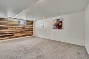 Carpeted spare room featuring wood accent wall and recessed lighting