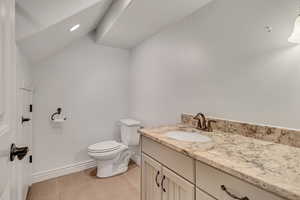 Bathroom featuring granite counters, vanity and vaulted ceiling
