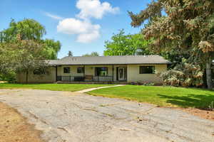 Ranch-style home with a porch, a front lawn, and brick siding