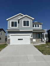 View of front facade with stone siding, an attached garage, and stucco siding