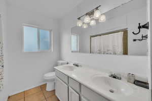 Bathroom with tile patterned flooring, double vanity, and a shower with curtain
