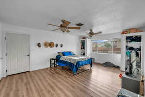 Bedroom with light wood finished floors, a textured ceiling, and a ceiling fan