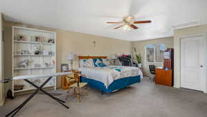 Bedroom featuring carpet floors, attic access, and ceiling fan