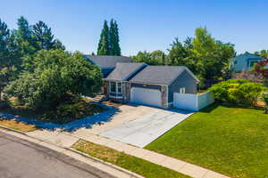 View of front of property featuring an attached garage, concrete driveway, and roof with shingles