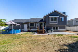 Back of house with entry steps, an outdoor pool, a patio area, a chimney, and roof with shingles