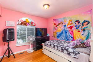 Bedroom with wood finished floors and baseboards