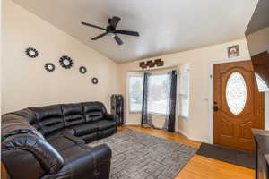 Living area featuring lofted ceiling, a ceiling fan, and wood finished floors