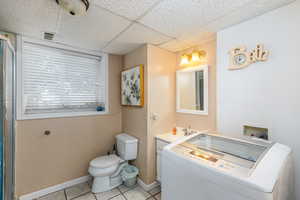 Bathroom with washer / clothes dryer, vanity, tile patterned floors, and a paneled ceiling