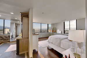 Bedroom featuring multiple windows, dark wood-style floors, recessed lighting, a mountain view, and a wall of windows